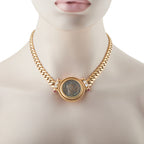 Gold tone chain necklace with round coin medallion and small red accents on sides