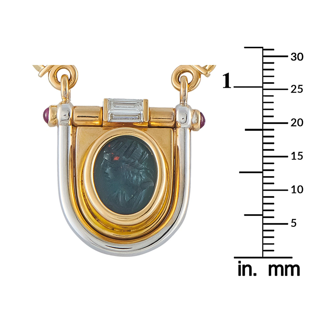 Gold shield pendant close-up with blue oval intaglio and baguette diamond accents
