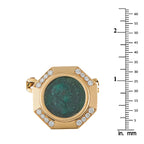 Gold coin pendant with green face and diamond accents beside size ruler