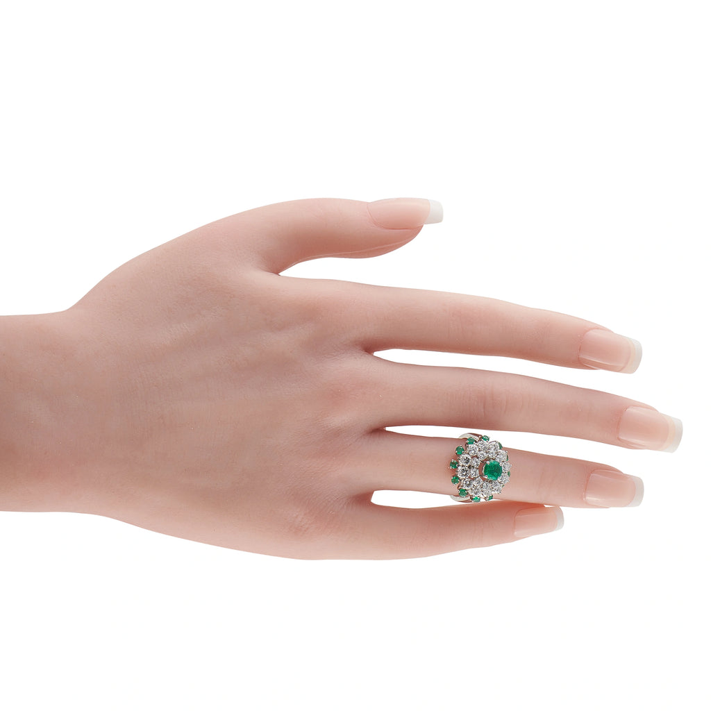 Platinum cluster ring with green emerald center and diamond halo on hand