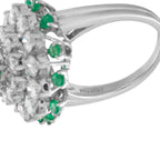 Platinum ring side view showing diamond cluster and small green emerald accents