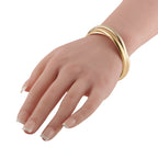 Tri-color 18K gold bangle on hand, polished rose, white, and yellow bands