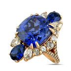 Rose gold ring with large blue sapphire, round diamonds, and marquise side stones