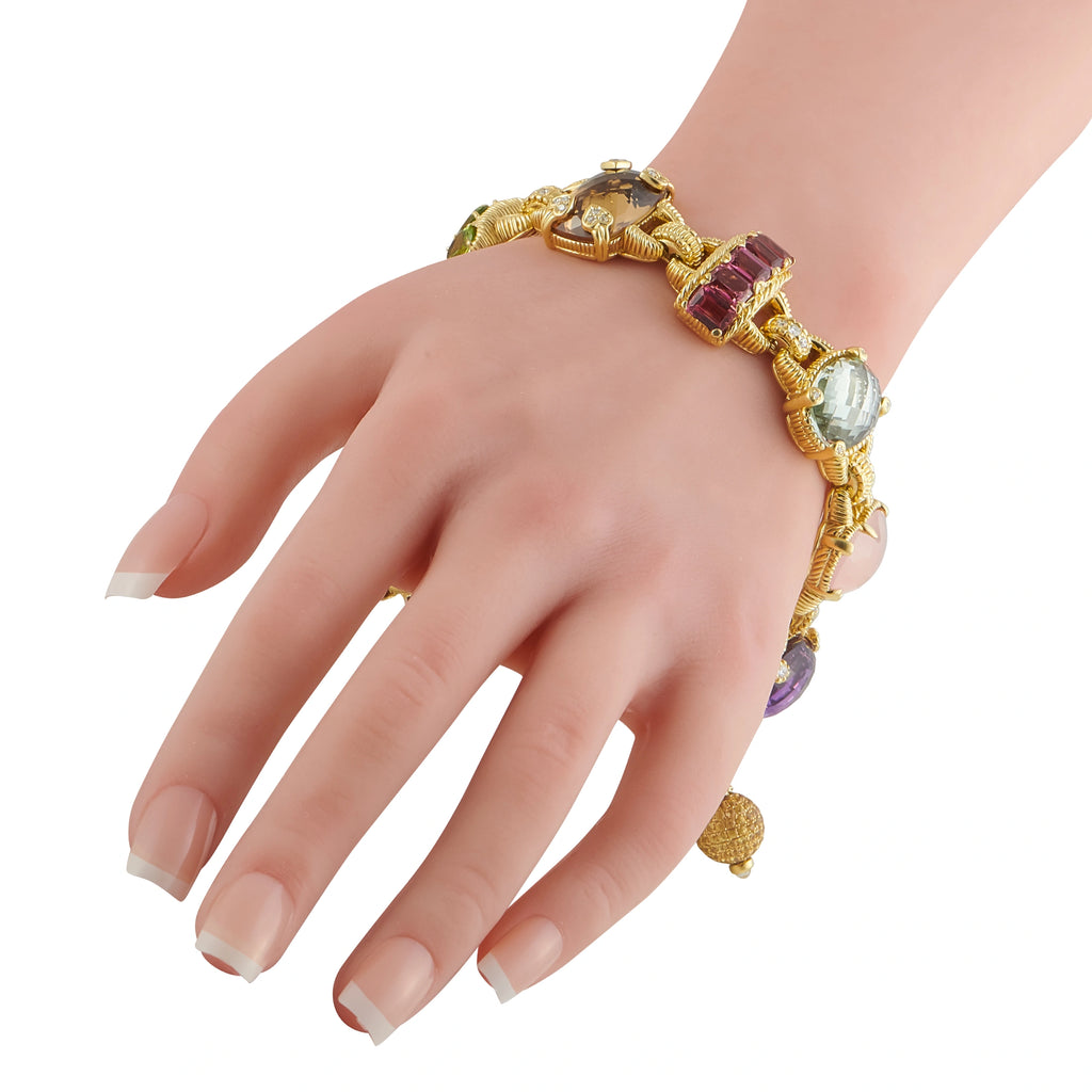 Gold bracelet worn on wrist with pink, purple, and blue gemstone charms