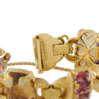 Gold bracelet clasp close-up with heart motif and faceted pink and blue stones