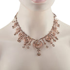 Rose gold diamond necklace on model with heart stations and floral fringe, V-shape
