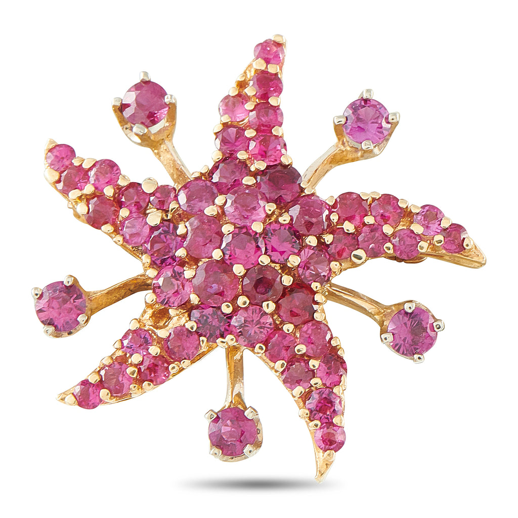 Star-shaped rose gold brooch with pink ruby-like stones and gold prongs.