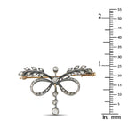 Diamond bow brooch on measuring scale, ornate loops and dangling round stone