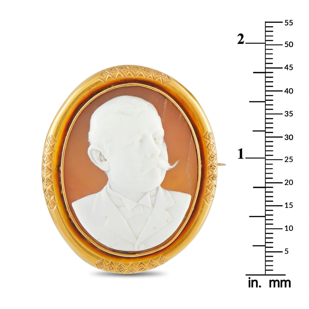 Antique oval cameo brooch with white relief portrait in gold frame; size shown with ruler