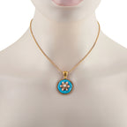 Gold tone necklace with round blue enamel pendant and coral-like floral accents