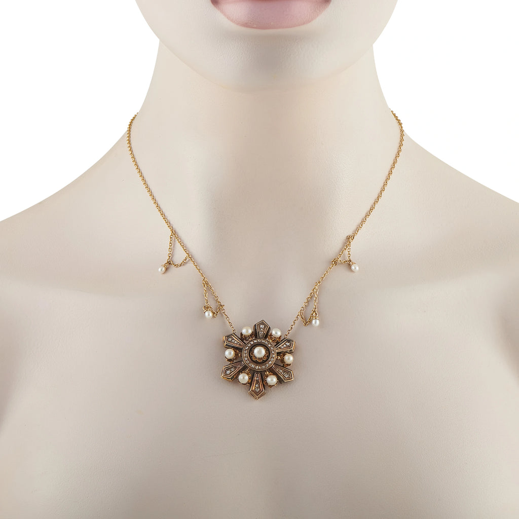 Gold tone necklace on mannequin with central filigree cross pendant and pearl accents