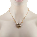 Gold tone necklace on mannequin with central filigree cross pendant and pearl accents