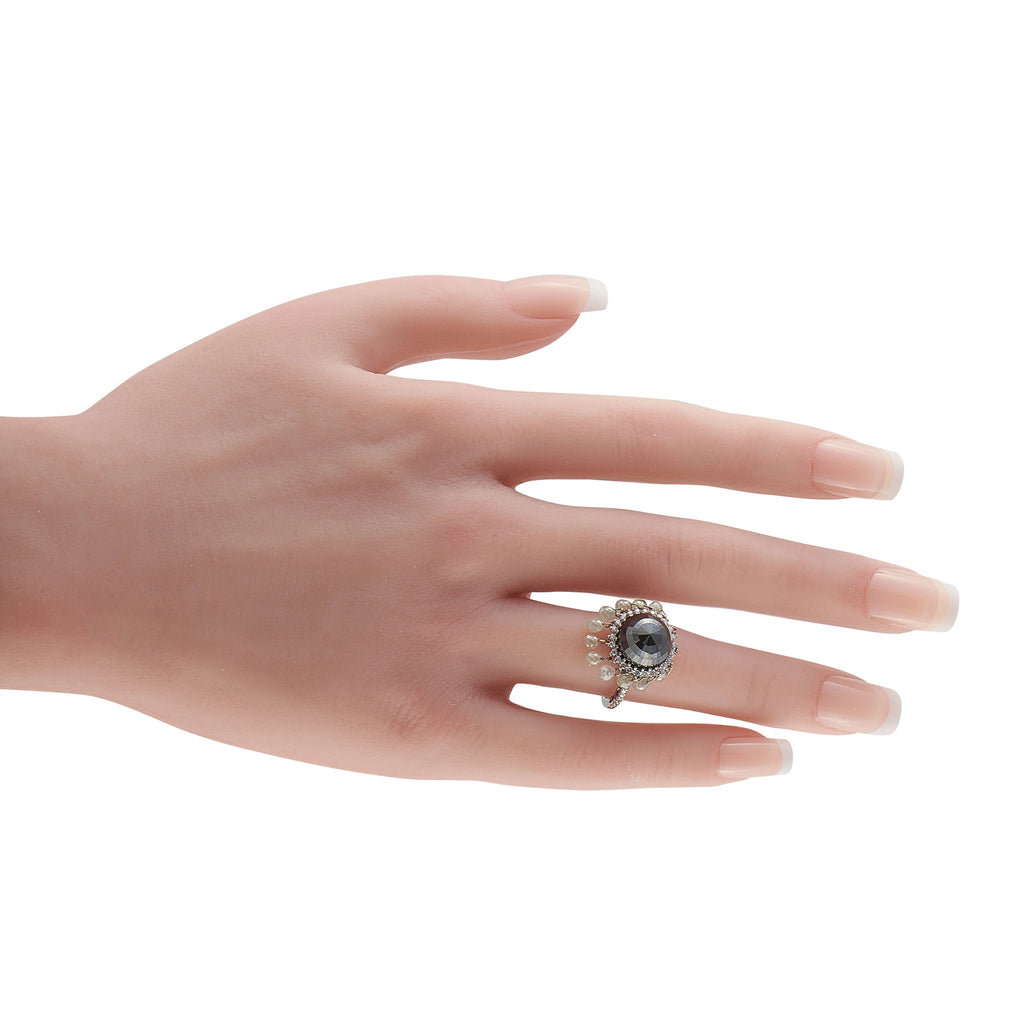 18K white gold diamond ring on hand, dark center stone with white halo and drop accents