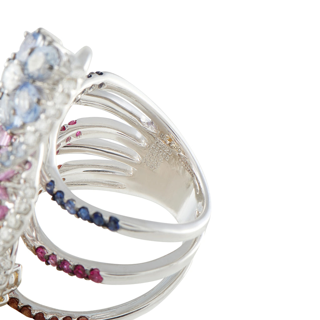 White gold ring with curved band and small blue, pink, and brown sapphires