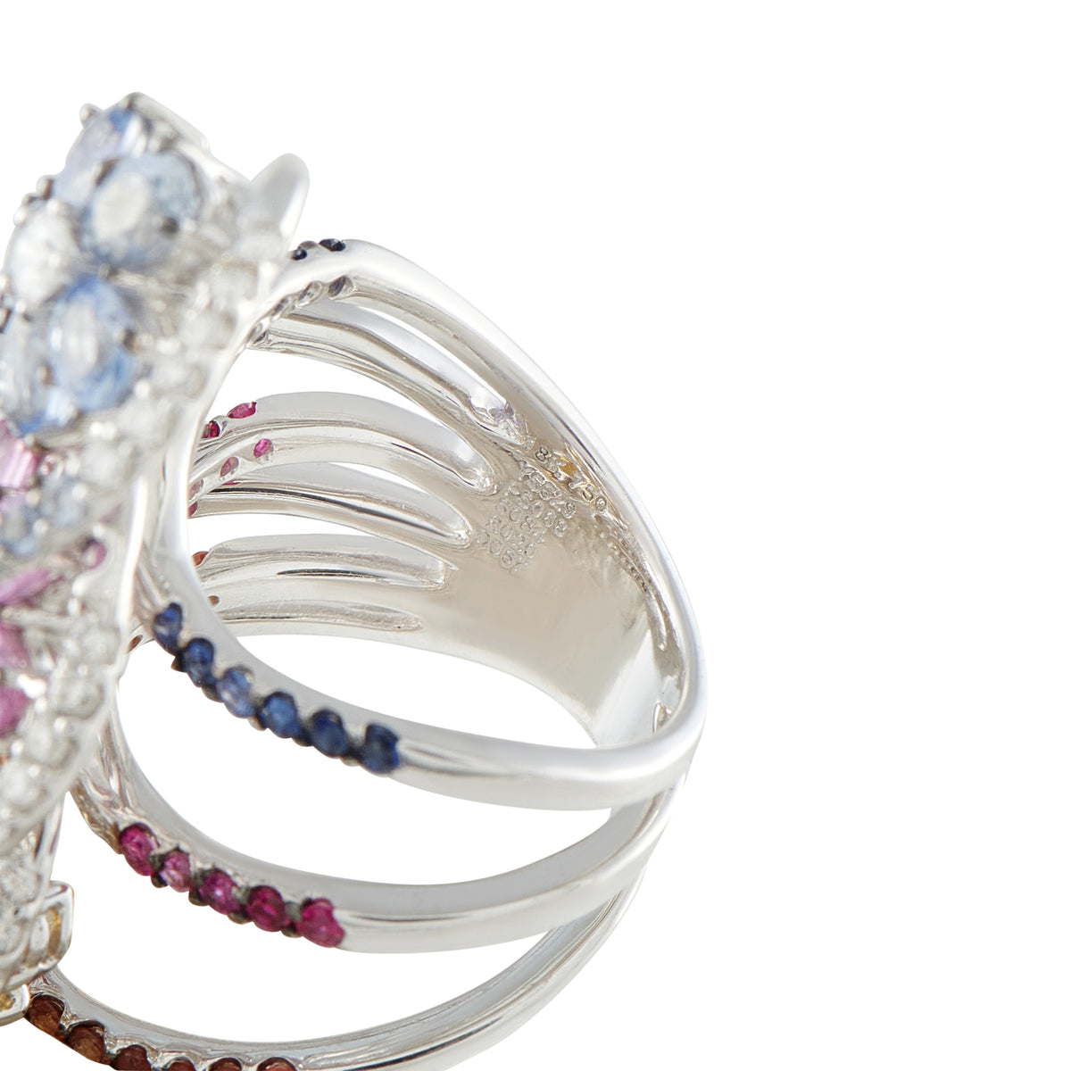 White gold ring with curved band and small blue, pink, and brown sapphires