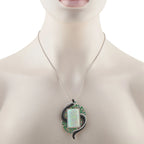 Opal centerpiece pendant in white gold with green gemstone halo and black enamel accents