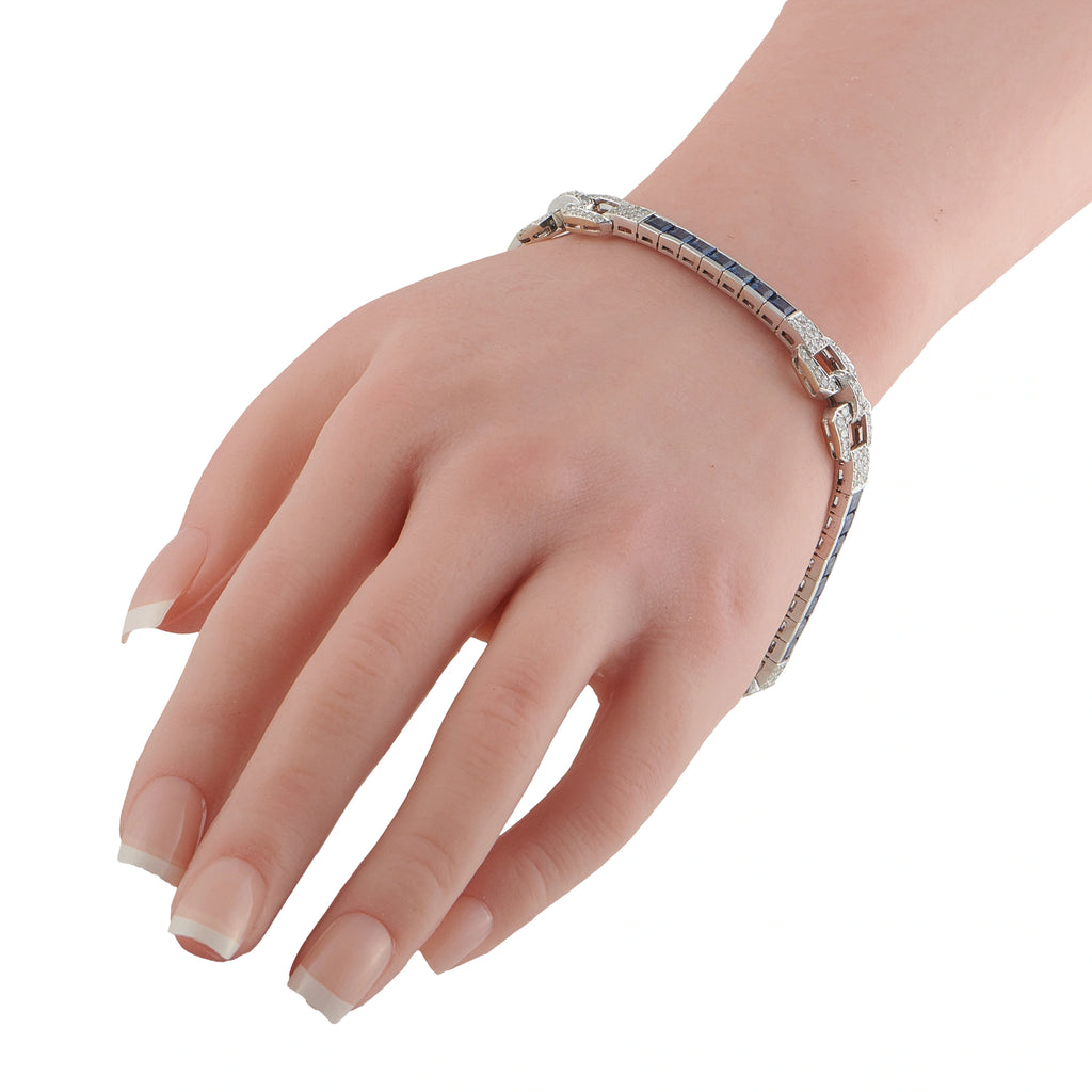 Art Deco white gold bracelet worn on hand, blue sapphire insets and diamond geometric links