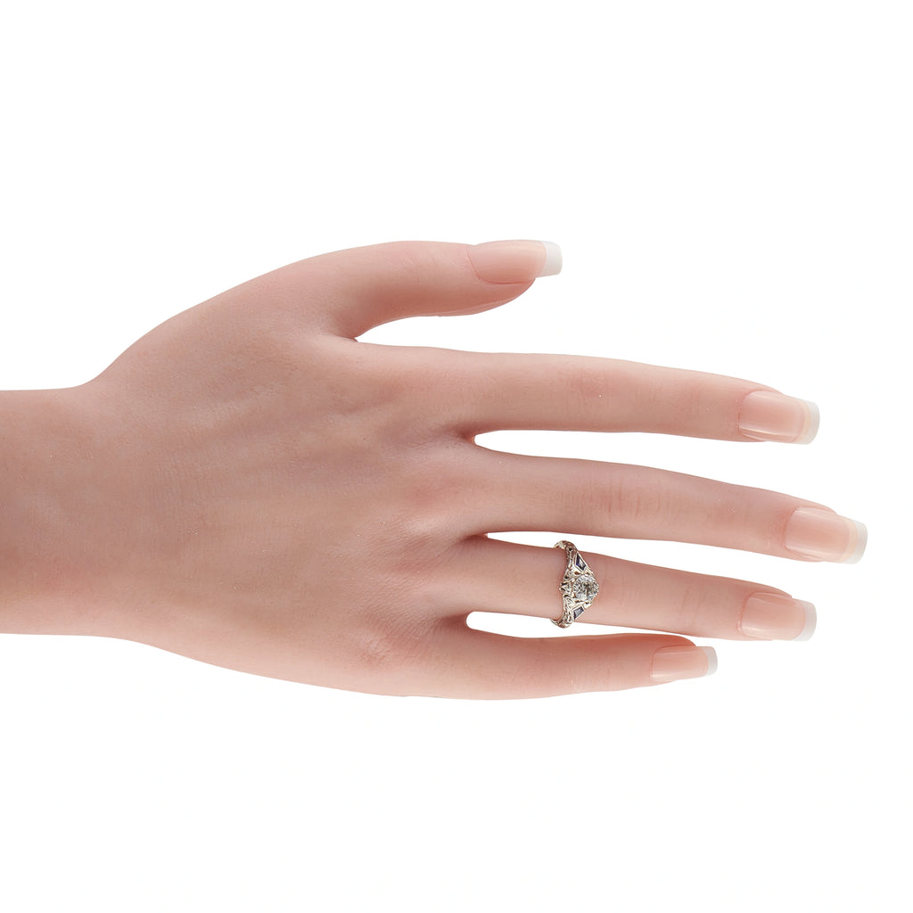 Art Deco 18K white gold diamond ring with blue accents worn on finger