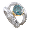 Two-tone gold diamond ring with round blue-green gemstone and baguette stone band
