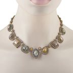 Yellow gold diamond halo necklace on mannequin with linked oval and pear stones