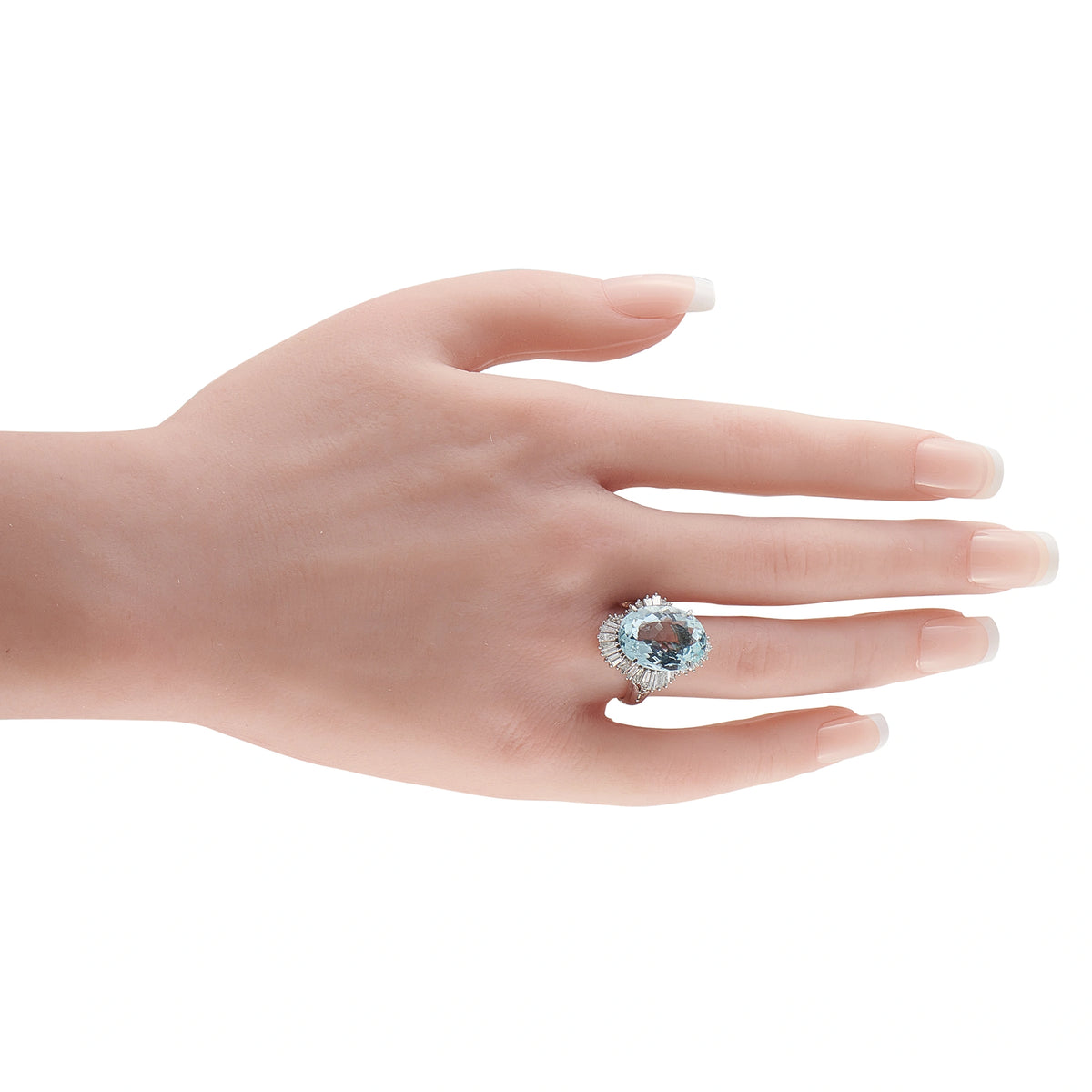 Aquamarine and diamond ring worn on a hand, showing its oval center stone