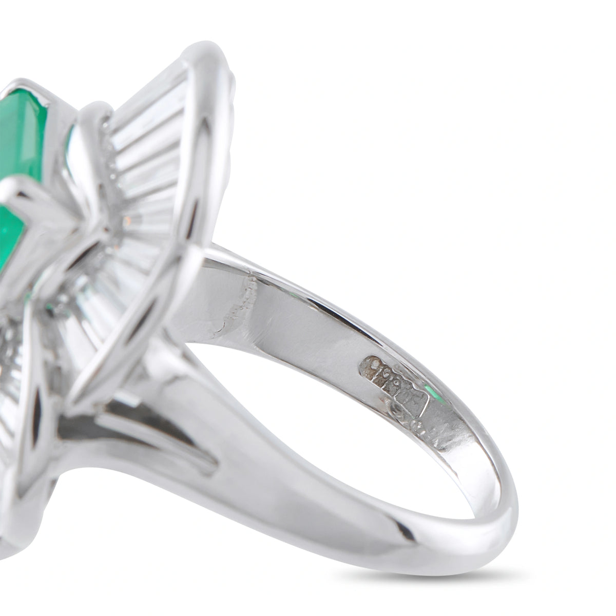 Platinum ballerina ring close-up of band, prongs, and emerald-cut green gemstone