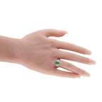Green jade and diamond halo ring on hand; oval center stone with prong setting