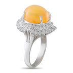 Diamond halo ring featuring oval orange-yellow opal cabochon with openwork platinum band