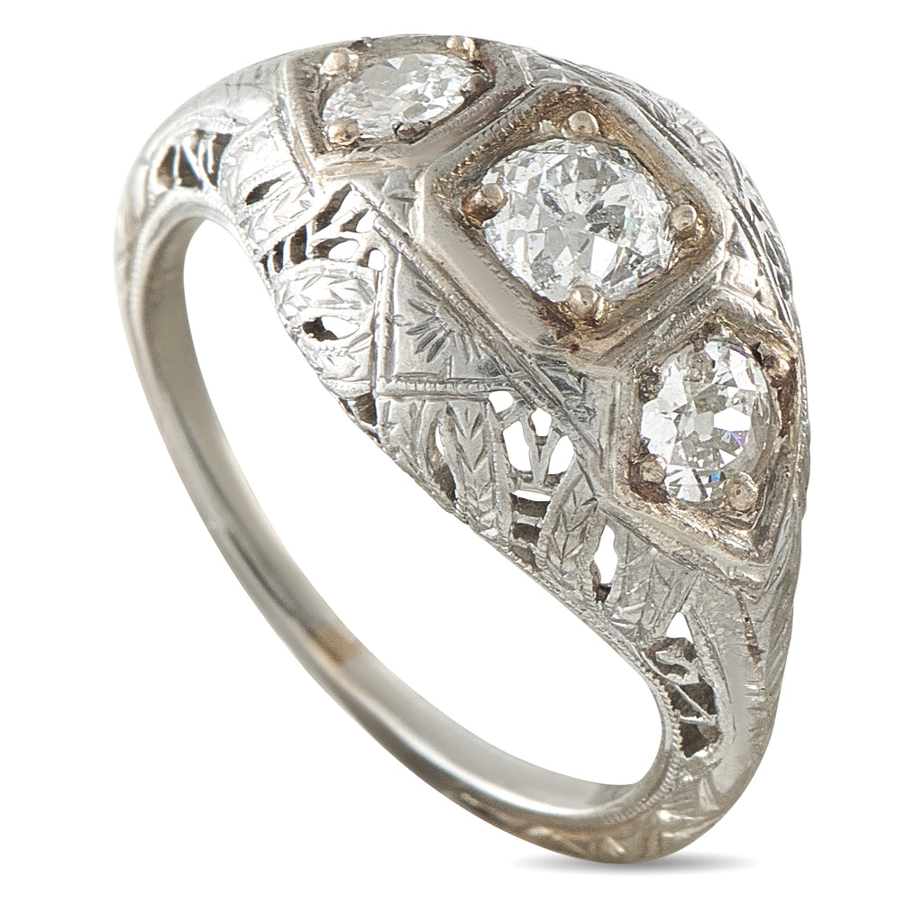 Platinum three-stone diamond ring with ornate engraved band and three round center stones