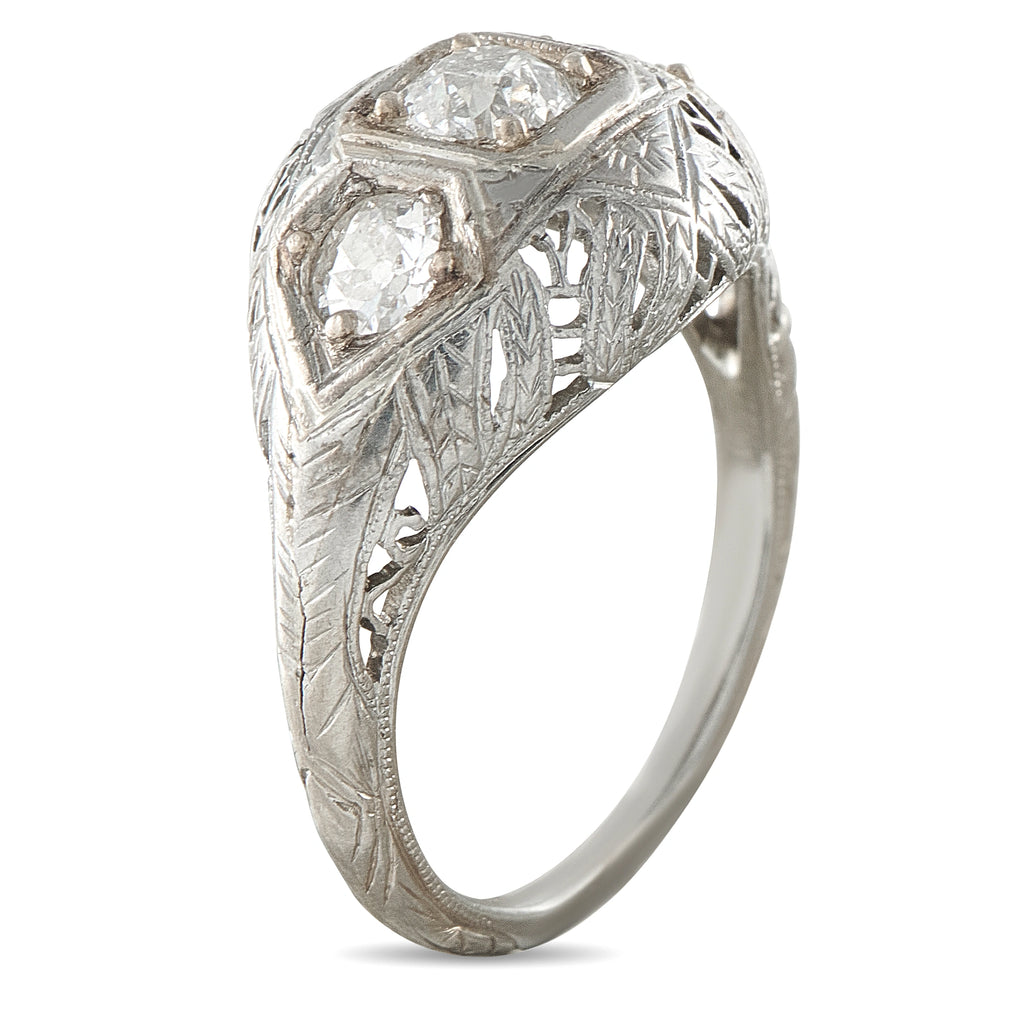 Platinum three-stone diamond ring with leaf motif engraving and domed settings
