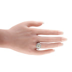 Cushion-cut diamond ring worn on a hand, with a halo and platinum band