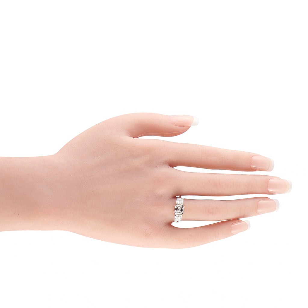 Platinum diamond ring on hand, three emerald-cut stones