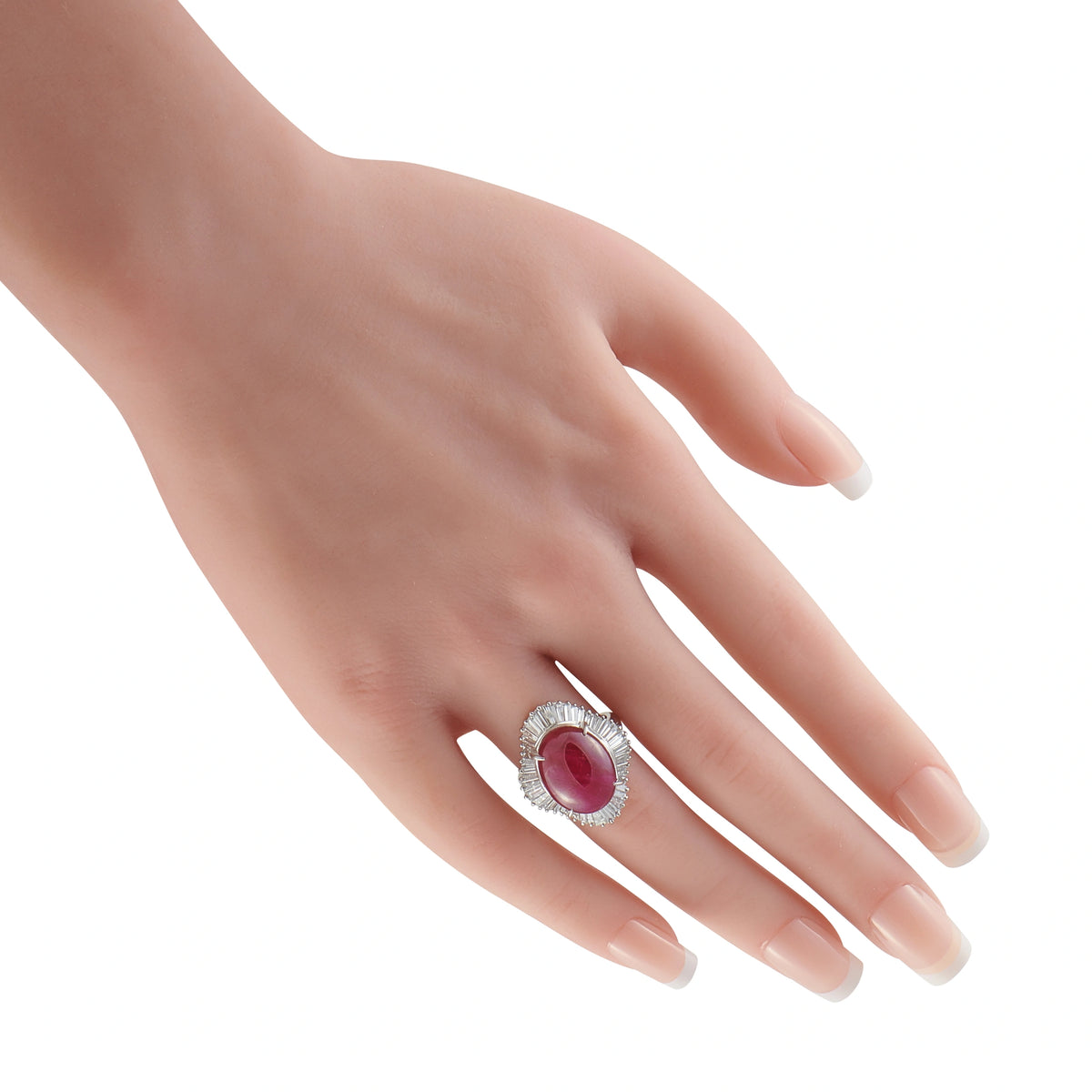 Platinum ruby and diamond ring worn on a finger, with an oval center stone and diamond halo