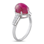 Platinum-toned ring with pink oval cabochon ruby bezel and baguette diamond shoulders