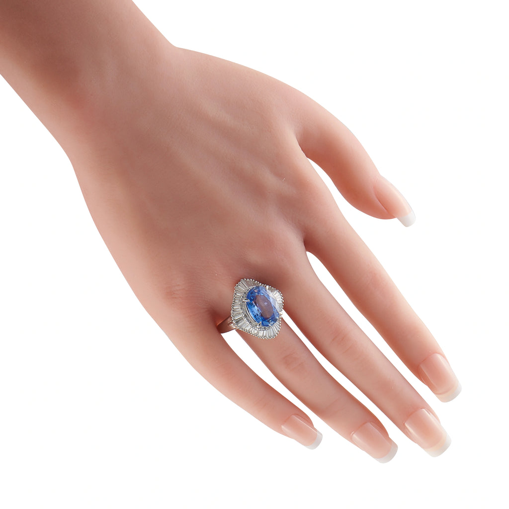 Oval blue sapphire and diamond ring shown on a hand
