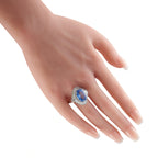 Oval blue sapphire and diamond ring shown on a hand