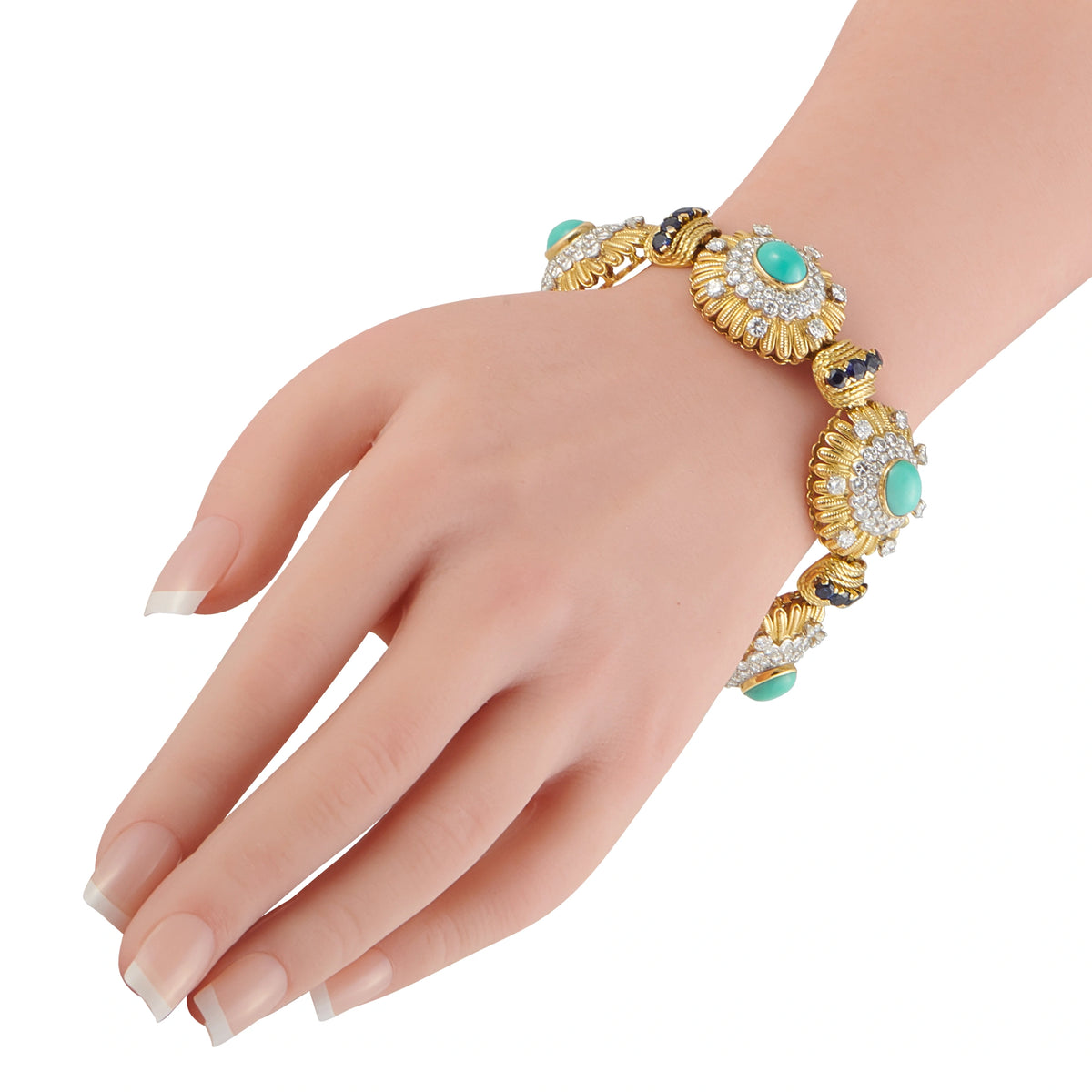 Gold bracelet on wrist with turquoise cabochons and sapphire blue accents