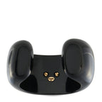 Black cuff bracelet with gold logo studs on side, curved glossy finish