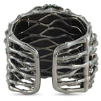 Openwork white gold cuff bracelet with dark interior backing and prong-set green accents
