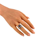 Platinum diamond-and-sapphire flower ring on hand, small blue center stone with halo diamonds