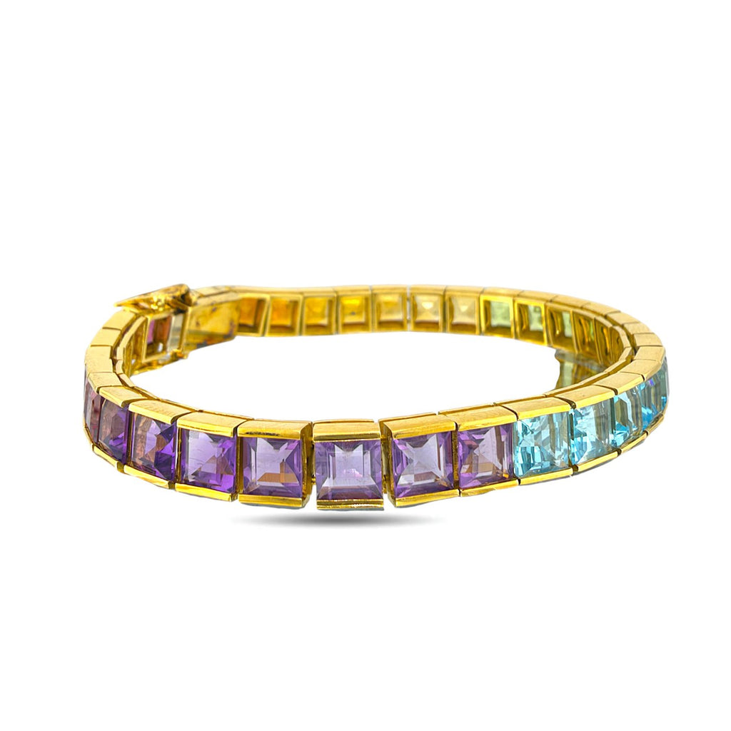 18K yellow gold rainbow gemstone tennis bracelet with a row of purple and blue stones