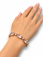 Rose gold bracelet with oval pink stones and diamond accents on an open hand