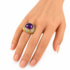 Amethyst and diamond ring on hand, yellow gold with green oval stone accents