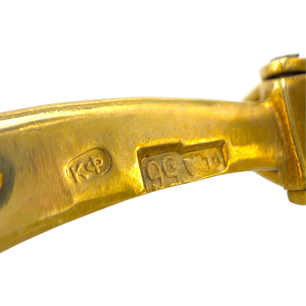 Gold cufflink bar with engraved marks, close-up of the underside fastening