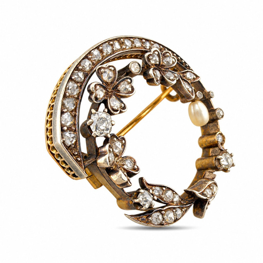 Angled view of the floral brooch showing diamond-set flowers, leaves, and a pearl drop