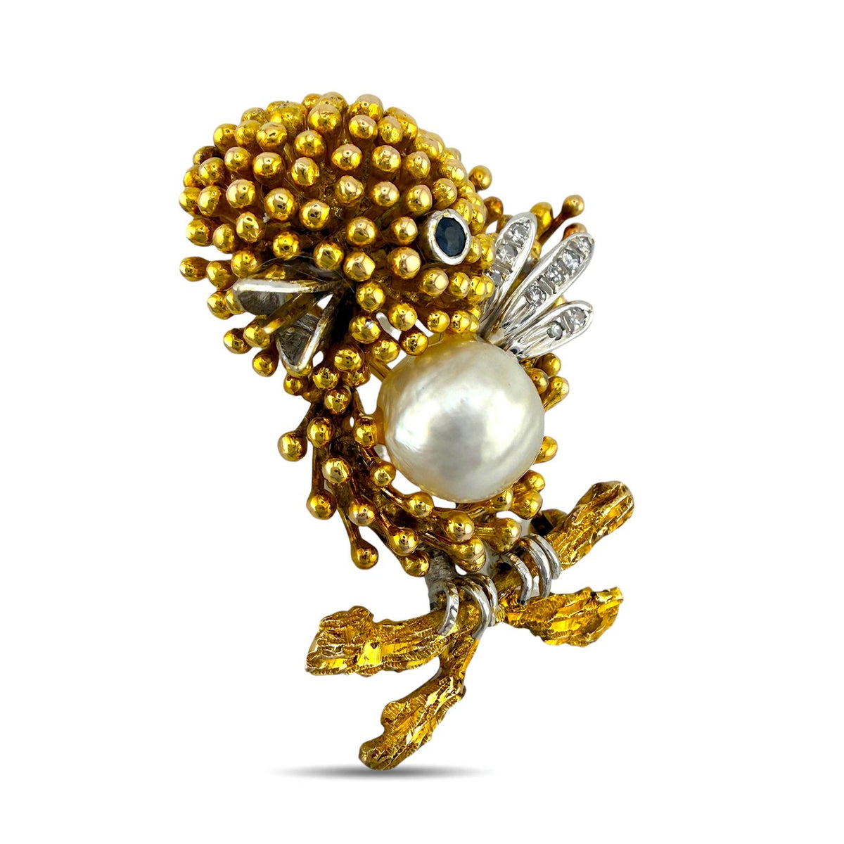 Gold-tone bird brooch with pearl centerpiece, blue sapphire eye, diamond wing detail