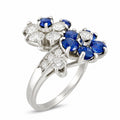 Platinum ring with diamond and sapphire flower clusters, three blue stones in front prongs