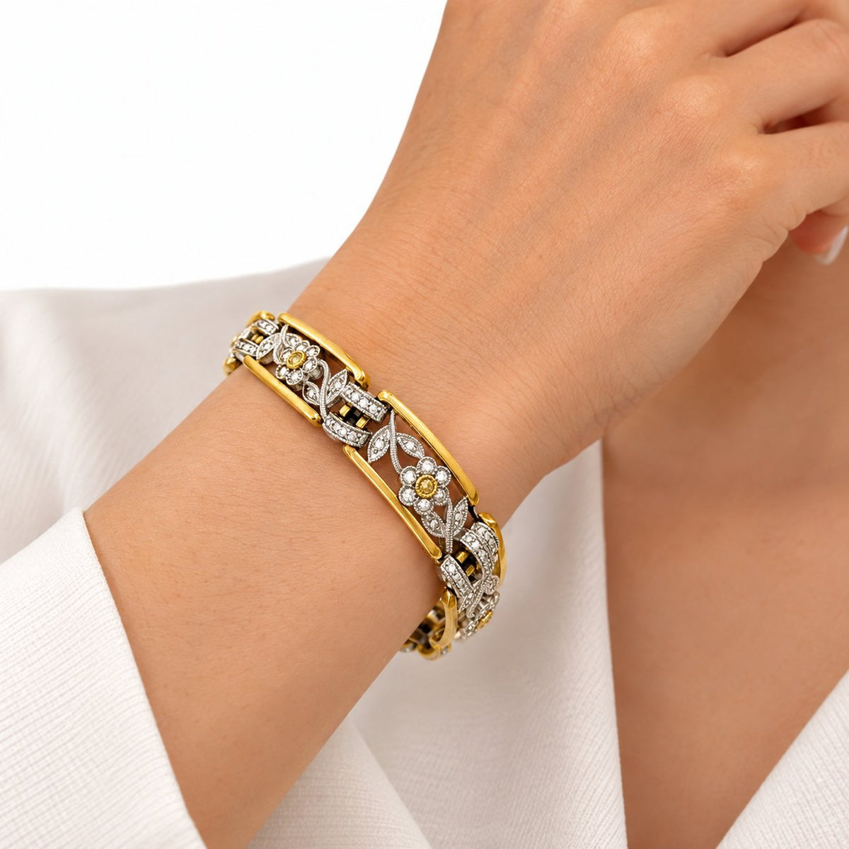 Diamond floral tennis bracelet in yellow and white gold worn on the wrist