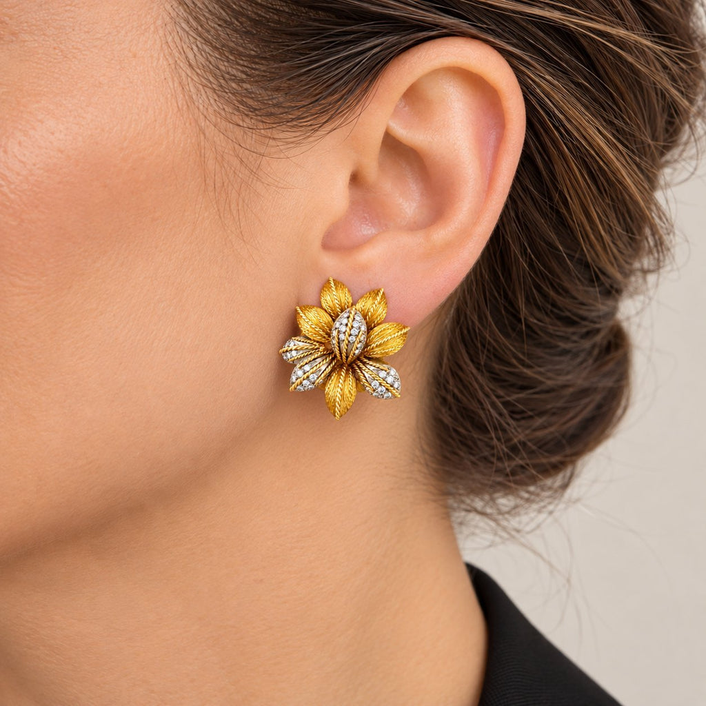 Yellow gold flower earring with diamonds worn on an ear