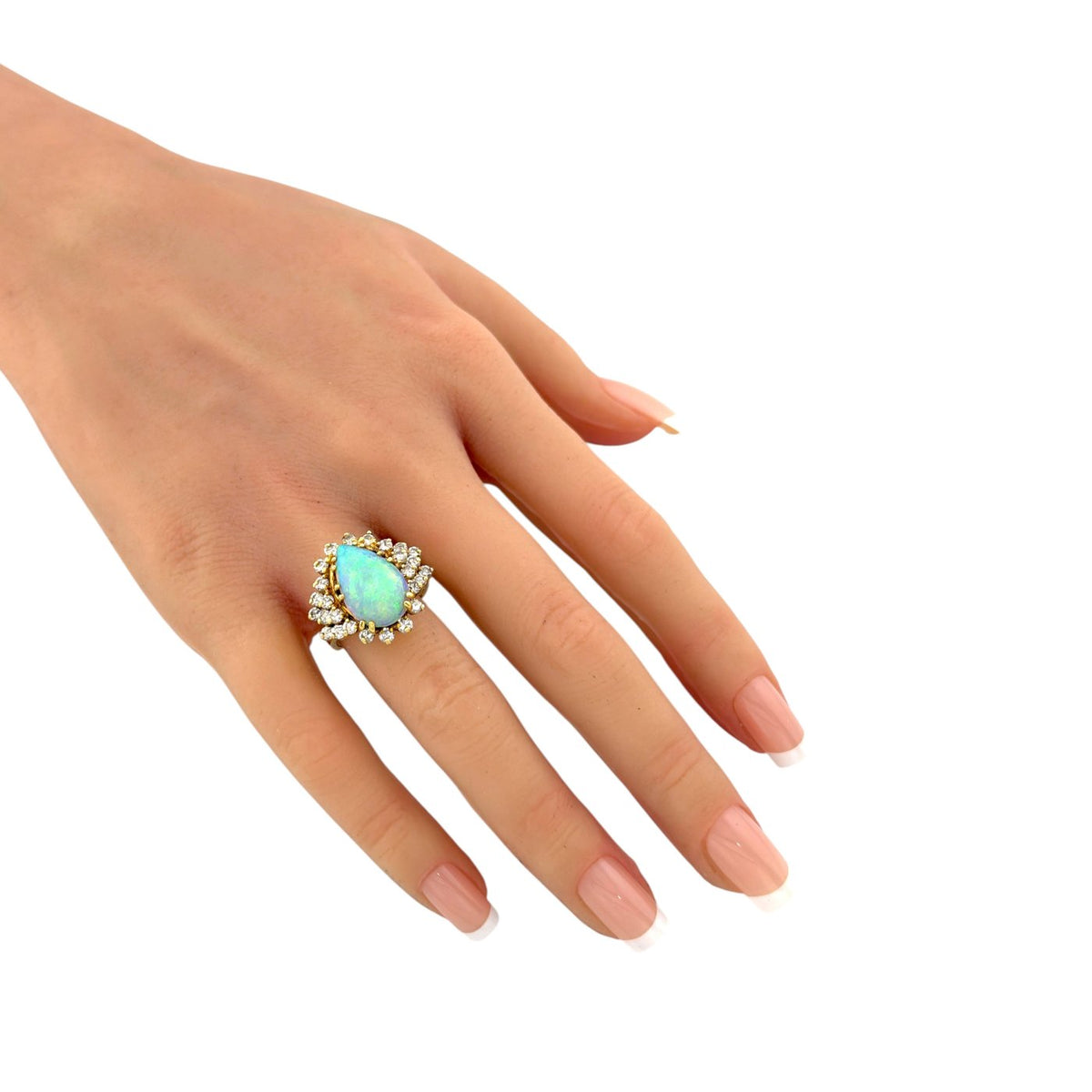 Close view of hand wearing an opal and diamond halo ring in yellow gold
